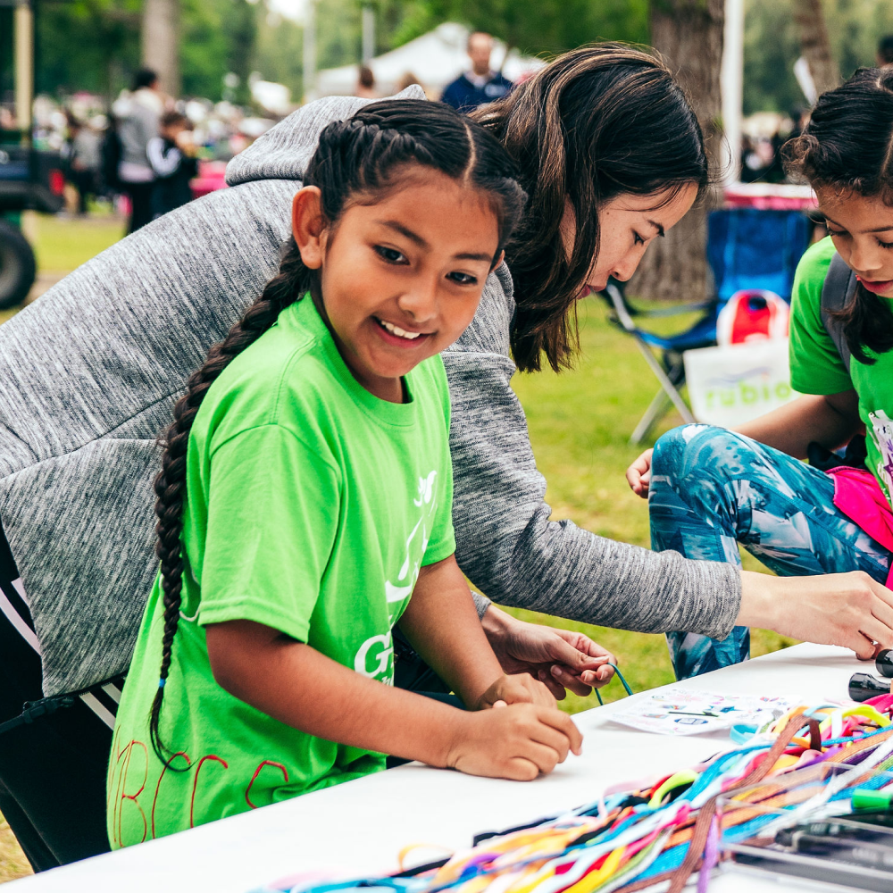 Two Girls on the Run participants smile while working with a volunteer